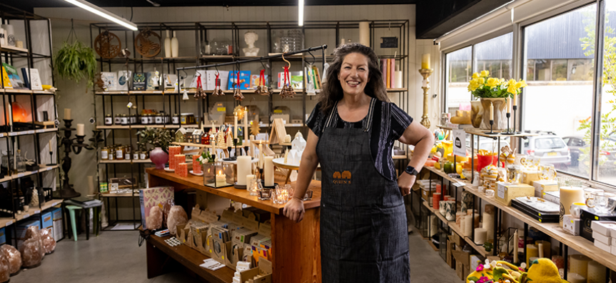 The owner of Queen B stands in her store with homemade products behind her