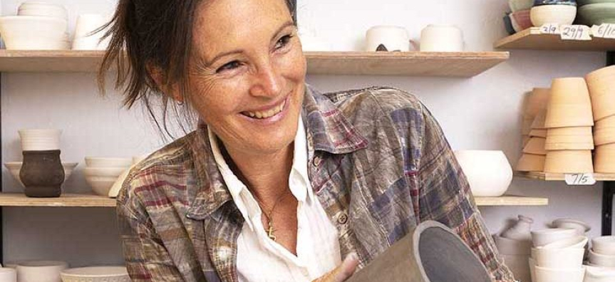 Artist in ceramics studio holding clay vessel