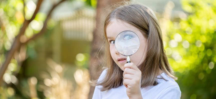 child looking through a magnifying glass