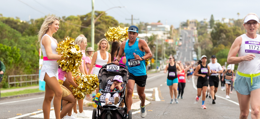 A father pushing his child in a pram running at Sun Run