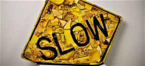Photo of an artwork, a street sign that reads 'slow', made out of pieces of discarded plastic