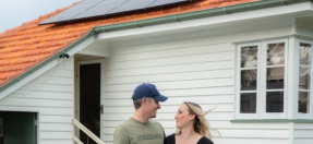 Two people standing in front of a house with solar panels on the roof