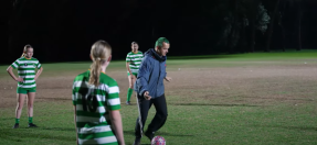 Coach kicking a ball with three players