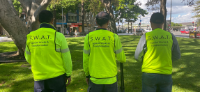 Three Council workers with their backs to the camera wear high-vis with printed wording: SWAT - Special Works and Transformation Team 