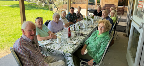 A group of seniors sits around a table for a Meals on Wheels community lunch