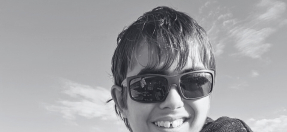 Photo of Luca Weber wearing sunglasses and smiling, the coastline behind him.