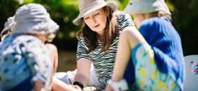 Female sitting on ground playing with pre schoolers