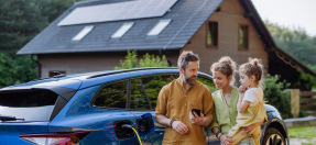 Family with electric car and solar panels on house