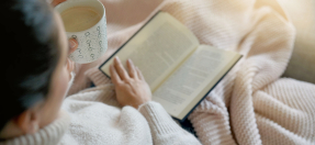 Woman reading a book with a hot beverage