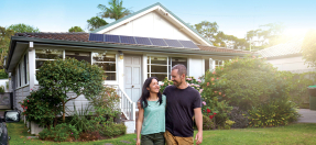 Two people standing in front of a house with solar panels on the roof