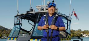 Jimmy Arteaga, volunteer at Marine Rescue Broken Bay stands in uniform in front of the rescue boat