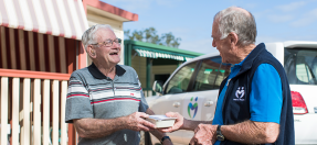 A Meals on Wheels volunteer and client smile together