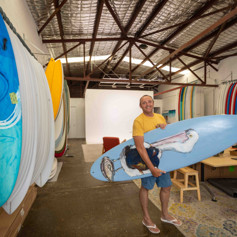 Owner of shop standing holding surf board