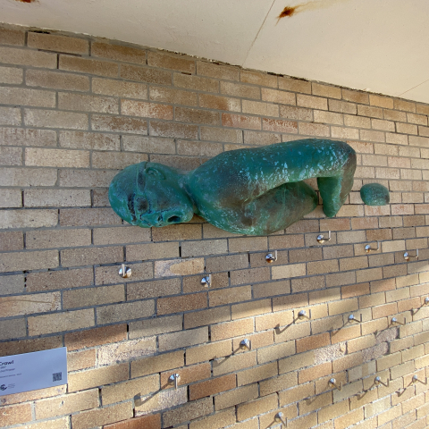 Bronze artwork of swimmer mounted on surf club wall